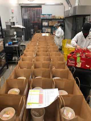 Workers assemble meal delivery bags for Great Plates Delivered Program