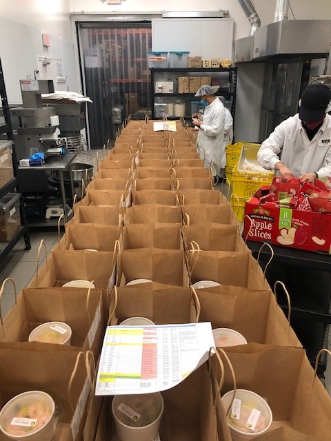 Workers assemble meal delivery bags for Great Plates Delivered Program