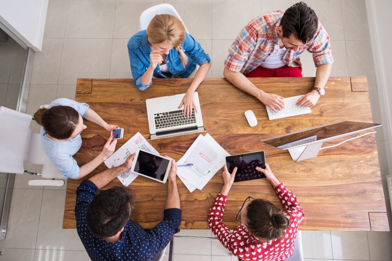 Five employees sit around a conference room table