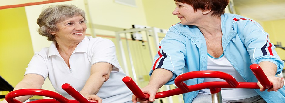 Two women on exercise bikes at the gym