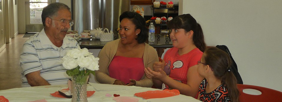 Older adult and youth sit to chat over tea