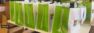 Computer distribution station with stacks of green Microsoft grocery bags