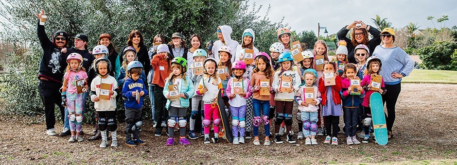 group of about 20 young girls in skateboarding gear holding signs with words of encouragement