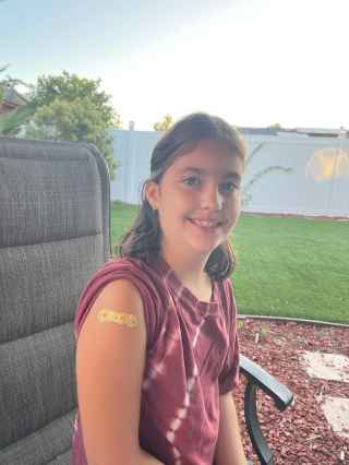 Young girl smiling with band aid on arm after flu vaccine